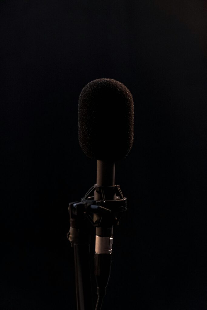 Close-up of a black microphone in a studio setting, isolated on a dark background.